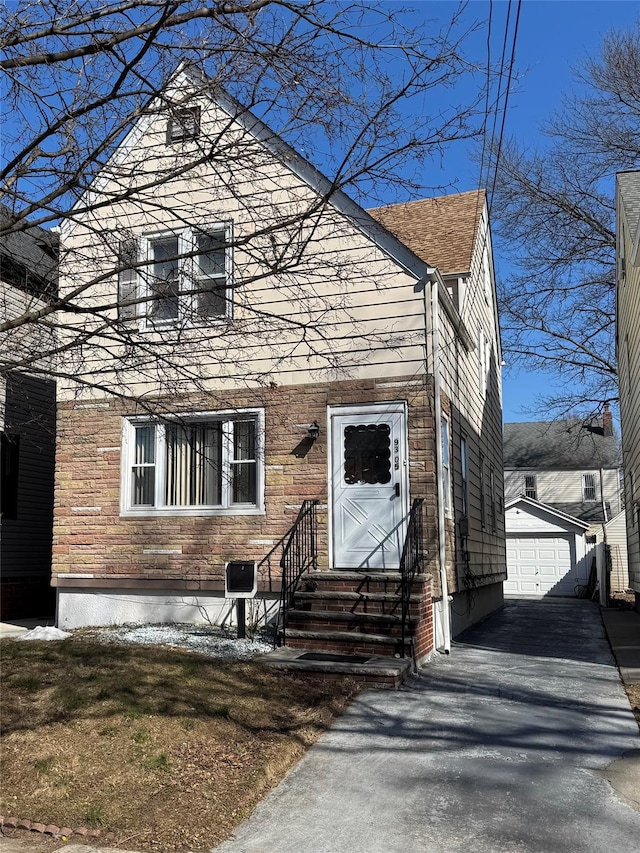 view of front of property featuring entry steps, stone siding, a detached garage, and an outbuilding