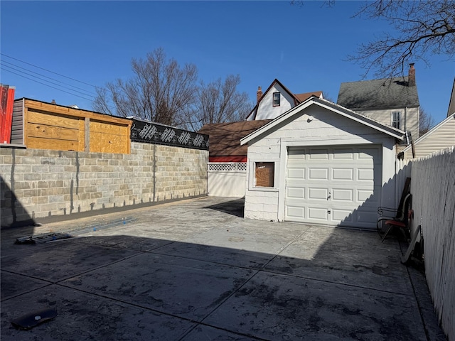 detached garage featuring driveway and fence