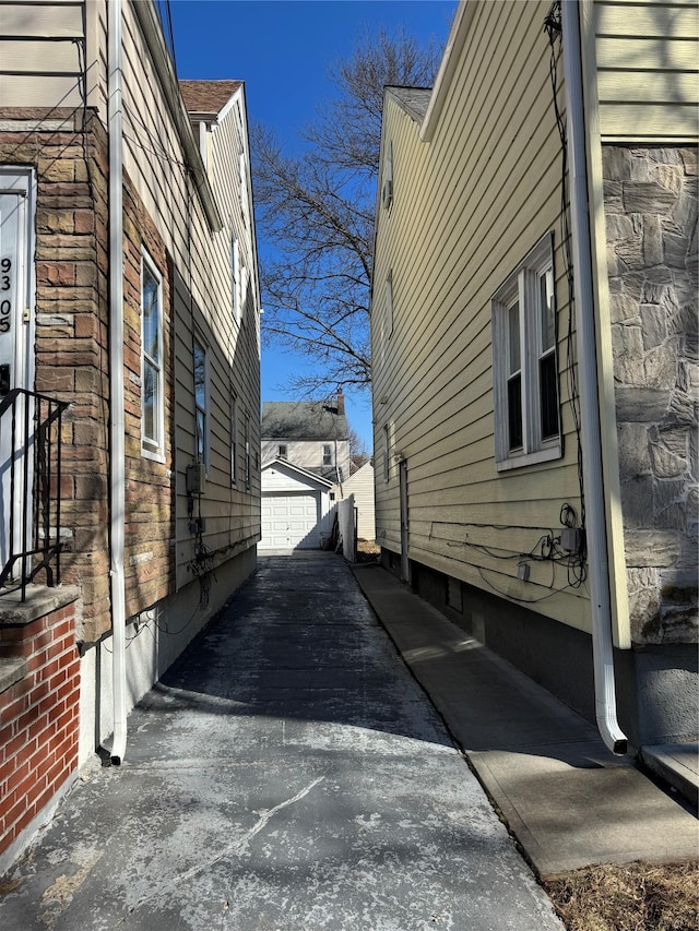 view of side of property with an outbuilding, stone siding, driveway, and a garage