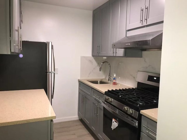 kitchen featuring a sink, stainless steel appliances, under cabinet range hood, and gray cabinets