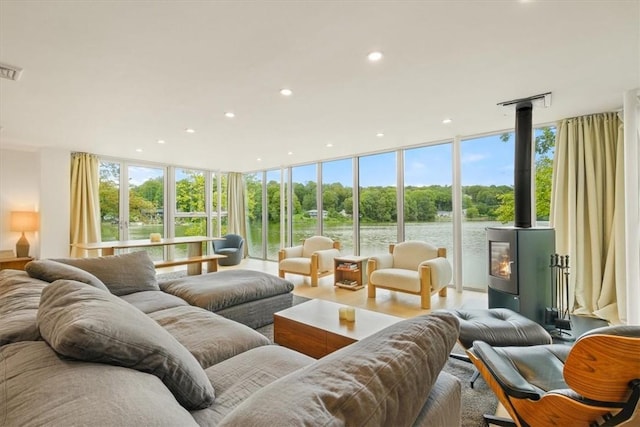 living room featuring a healthy amount of sunlight, recessed lighting, a wood stove, and floor to ceiling windows