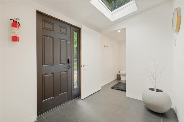 tiled entrance foyer with vaulted ceiling with skylight