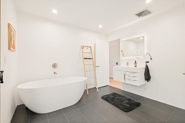 bathroom with visible vents, tile patterned floors, a freestanding bath, vanity, and recessed lighting