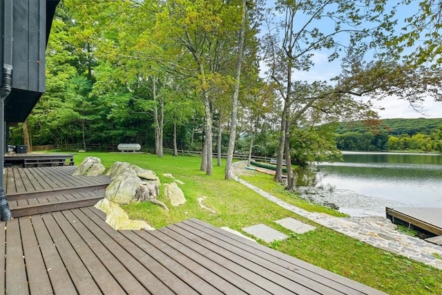 wooden terrace featuring a lawn and a water view