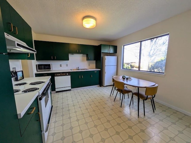 kitchen with white appliances, under cabinet range hood, green cabinets, and light countertops