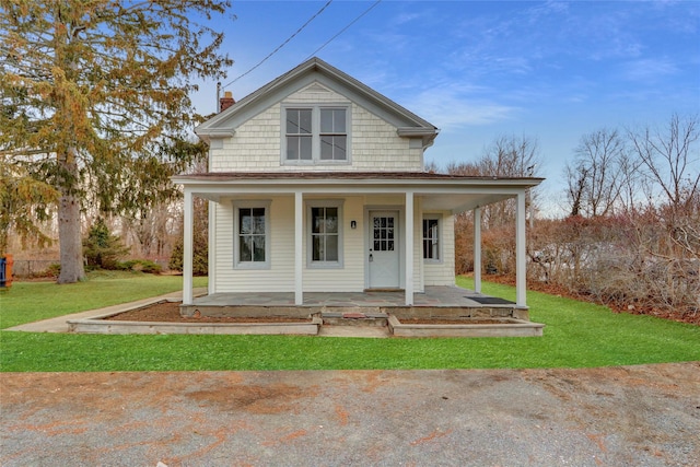 farmhouse with a chimney, a porch, and a front yard