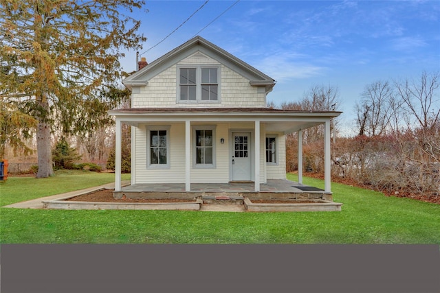 farmhouse-style home with covered porch, a chimney, and a front yard