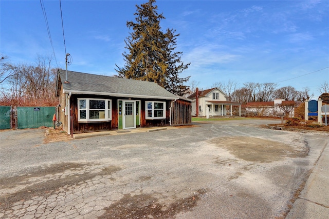 view of front of house with roof with shingles and fence