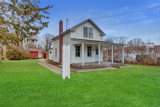 view of front facade with a porch, an outbuilding, a chimney, and a front lawn