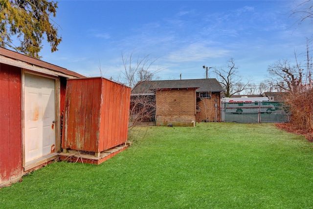 view of yard with an outbuilding, a gate, fence, and a storage shed