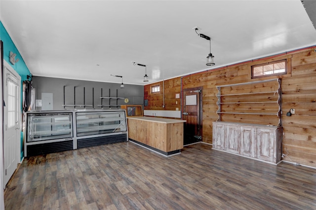 kitchen featuring wooden walls, dark wood finished floors, light countertops, and decorative light fixtures