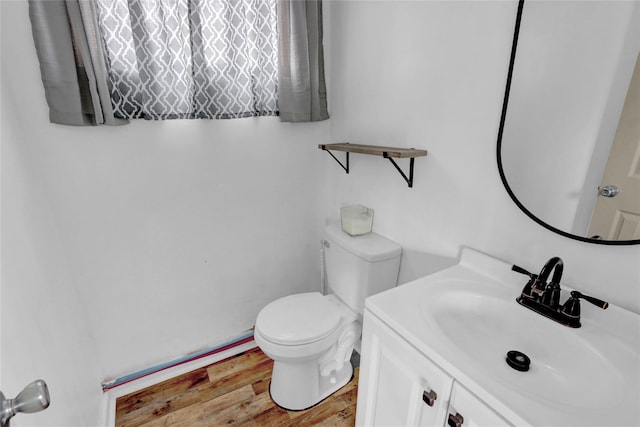 half bath featuring vanity, toilet, and wood finished floors