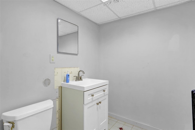 bathroom featuring toilet, vanity, a paneled ceiling, and baseboards