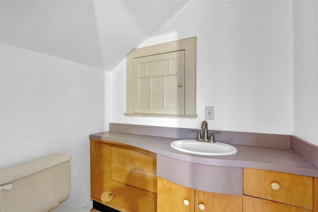 bathroom featuring lofted ceiling, toilet, and vanity