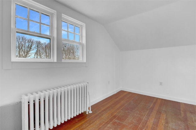 bonus room featuring lofted ceiling, radiator, wood-type flooring, and baseboards