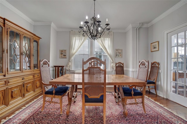 dining space featuring a chandelier, baseboards, wood finished floors, and crown molding