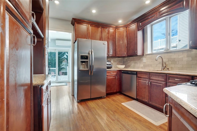 kitchen featuring stainless steel appliances, light wood finished floors, plenty of natural light, and a sink