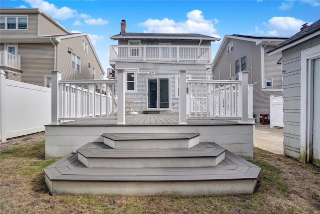 rear view of house featuring fence, a deck, and a balcony