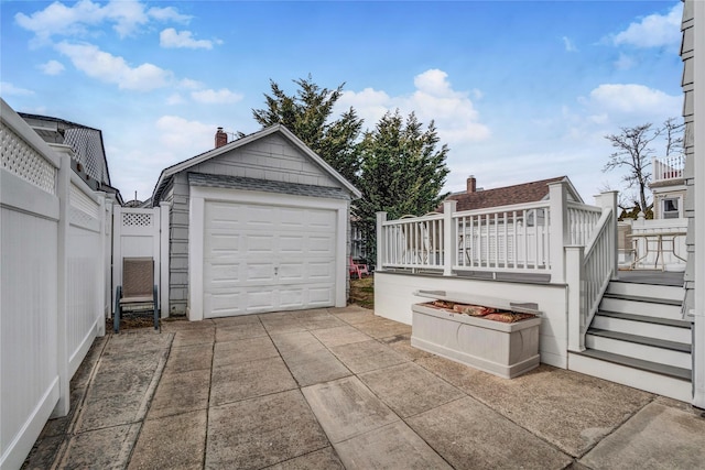 detached garage featuring fence and concrete driveway