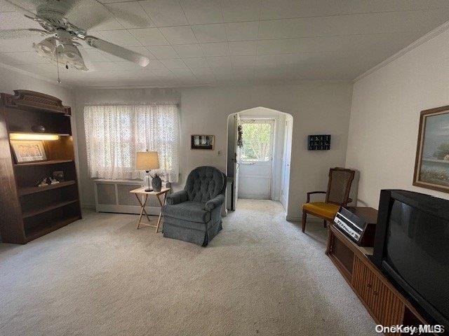 sitting room with arched walkways, ceiling fan, and carpet flooring