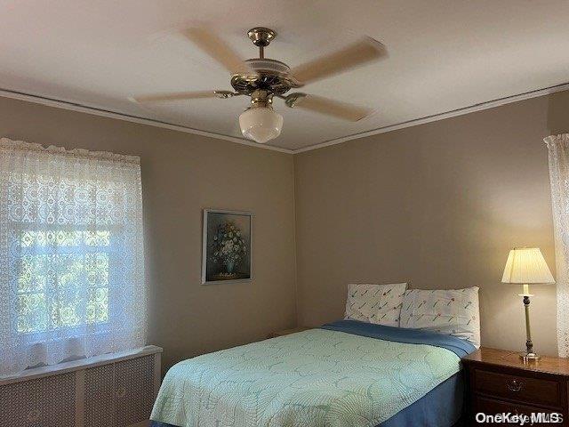 bedroom featuring radiator, ornamental molding, and a ceiling fan