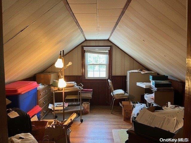 additional living space featuring vaulted ceiling, wooden walls, and wood finished floors