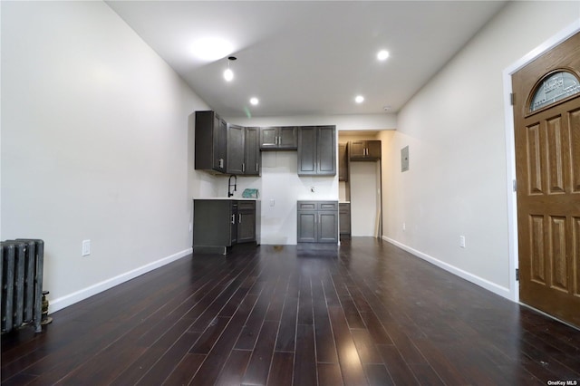 unfurnished living room with dark wood-type flooring, recessed lighting, a sink, and baseboards