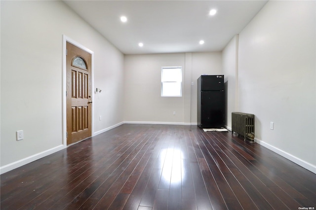 unfurnished living room featuring radiator heating unit, baseboards, dark wood finished floors, and recessed lighting