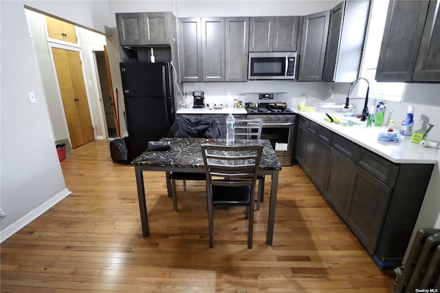 kitchen with baseboards, stainless steel appliances, light countertops, and light wood-style floors