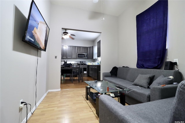 living room featuring a ceiling fan, light wood-style floors, and baseboards