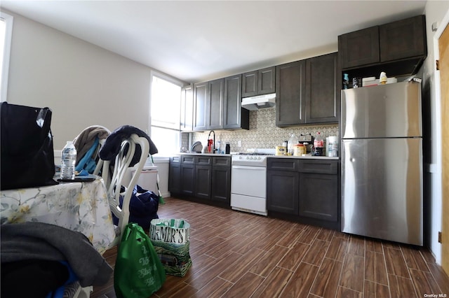 kitchen with white gas stove, light countertops, freestanding refrigerator, wood tiled floor, and under cabinet range hood