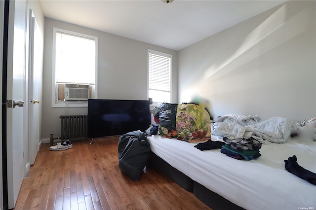 bedroom featuring wood-type flooring, cooling unit, and radiator