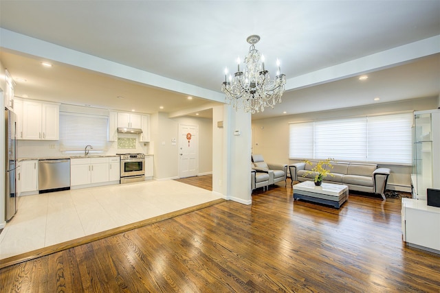 living room with a chandelier, a baseboard radiator, recessed lighting, wood finished floors, and baseboards