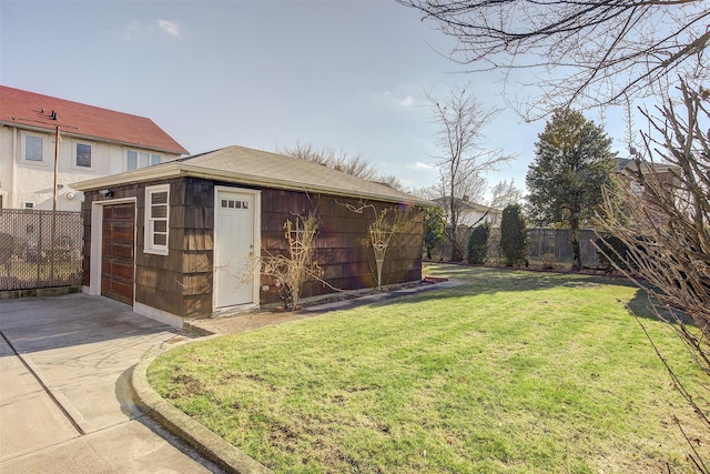 view of yard featuring a garage, driveway, an outdoor structure, and fence