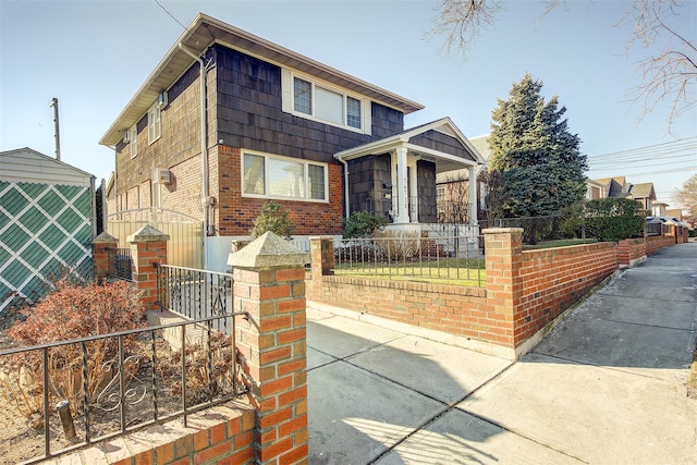 view of front of property with a fenced front yard, covered porch, and brick siding