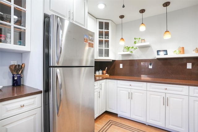 kitchen featuring glass insert cabinets, freestanding refrigerator, white cabinets, and dark countertops