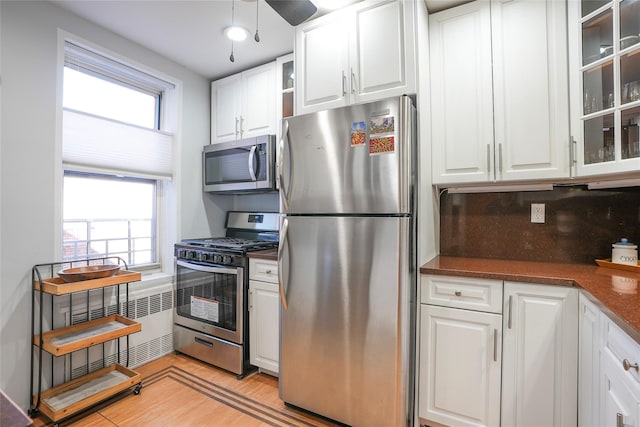 kitchen with stainless steel appliances, dark countertops, backsplash, and white cabinets