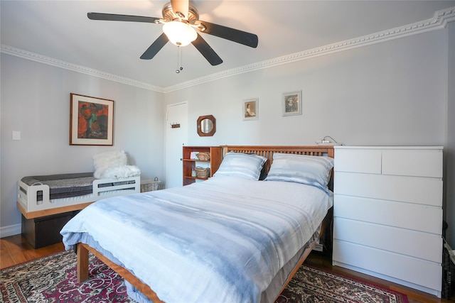 bedroom featuring ceiling fan, baseboards, wood finished floors, and crown molding