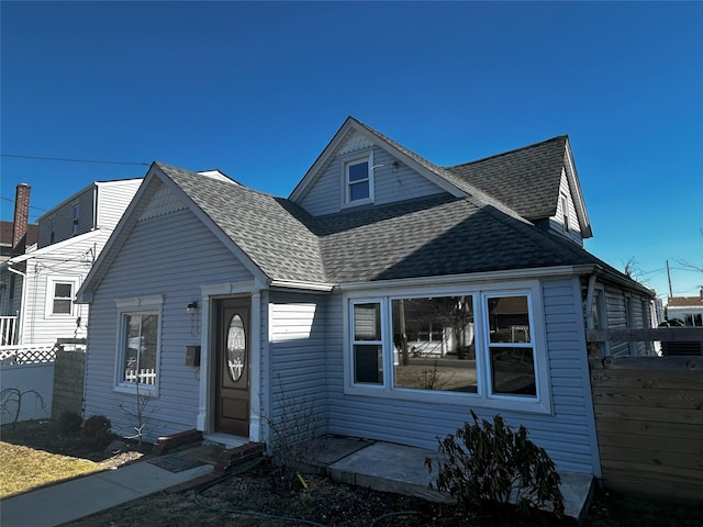 view of front of house featuring a shingled roof and fence