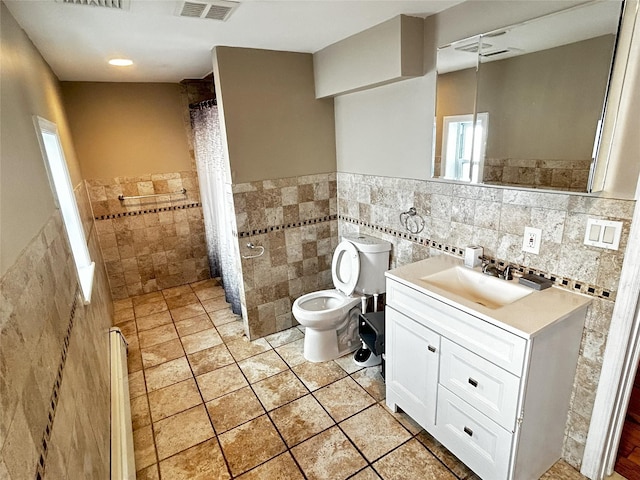 full bath with tile walls, visible vents, toilet, vanity, and tiled shower