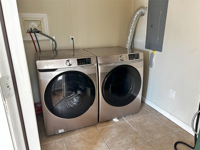 clothes washing area with laundry area, electric panel, baseboards, washer and clothes dryer, and tile patterned floors