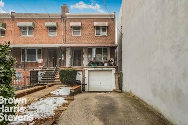 townhome / multi-family property featuring an attached garage, a chimney, concrete driveway, and brick siding