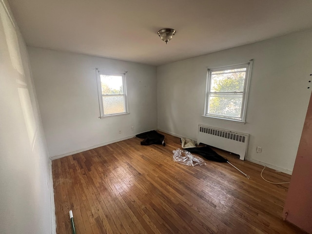 unfurnished room with radiator, baseboards, and hardwood / wood-style floors