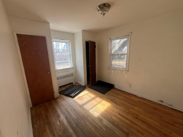 unfurnished bedroom with hardwood / wood-style flooring and radiator heating unit