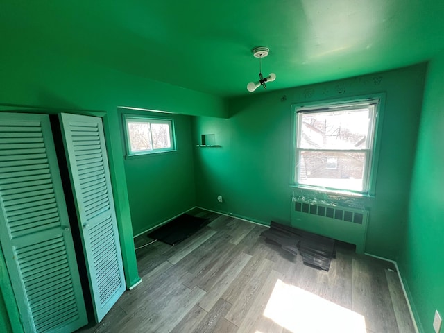 spare room featuring baseboards, radiator heating unit, and wood finished floors