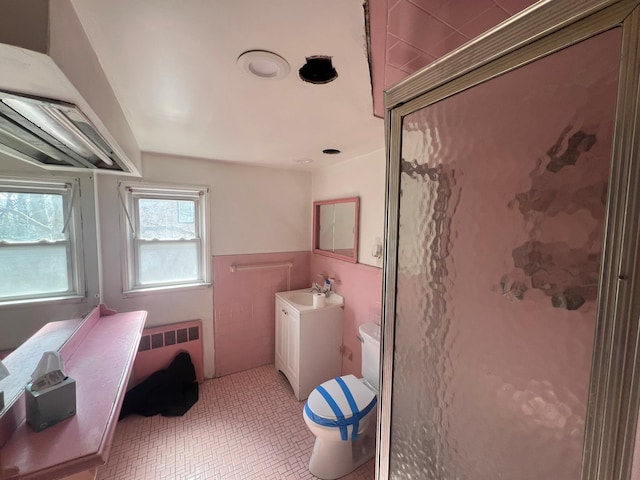 full bathroom featuring toilet, vanity, tile walls, a shower stall, and radiator heating unit