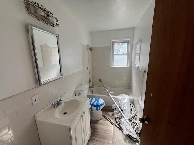 full bath with shower / bathtub combination, toilet, wood finished floors, vanity, and tile walls