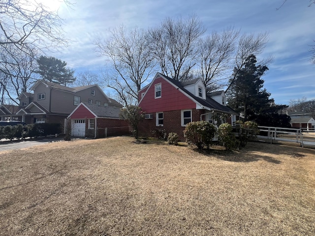 view of property exterior featuring a garage, brick siding, fence, and a lawn