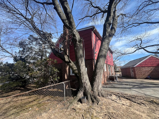 view of property exterior with fence, an outdoor structure, and brick siding