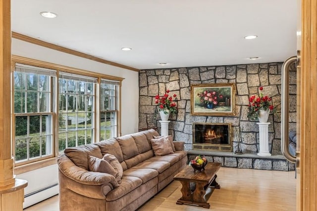 living area featuring wood finished floors, a baseboard radiator, a fireplace, and crown molding